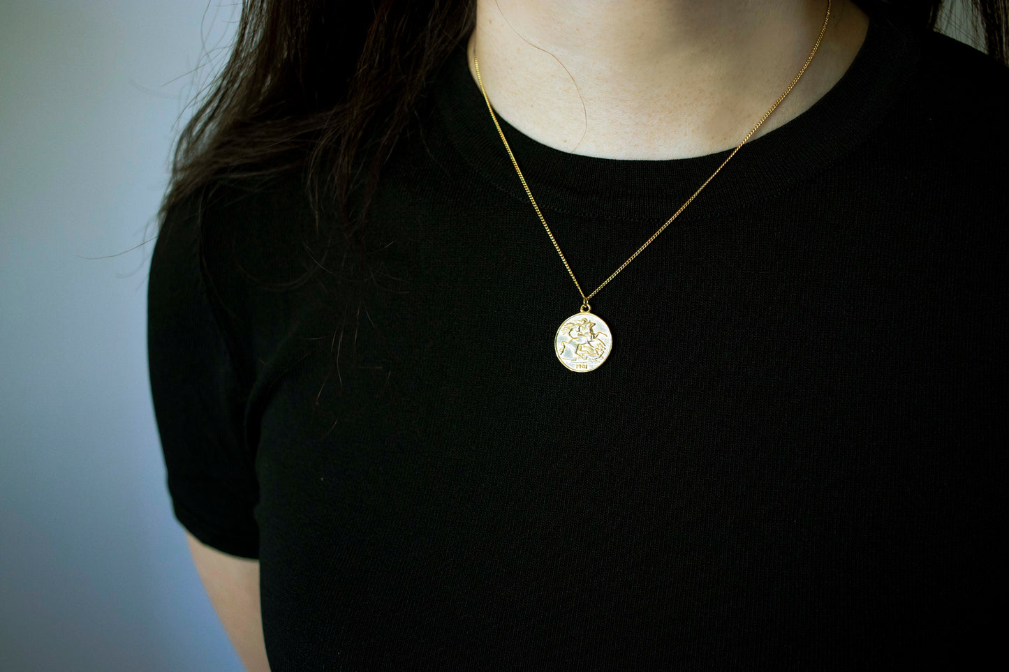 The necklace is adorned with a coin, layer with a relief of a queen and a flying horse on the reverse side.
