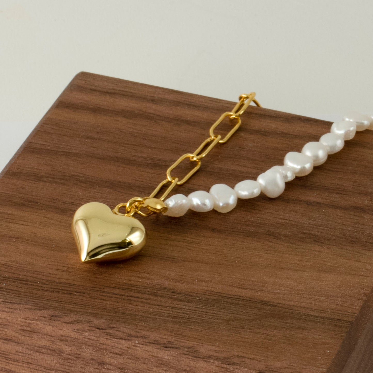 This stylish piece features a half chain with baroque pearls and other half an alta chain with a heart pendant.