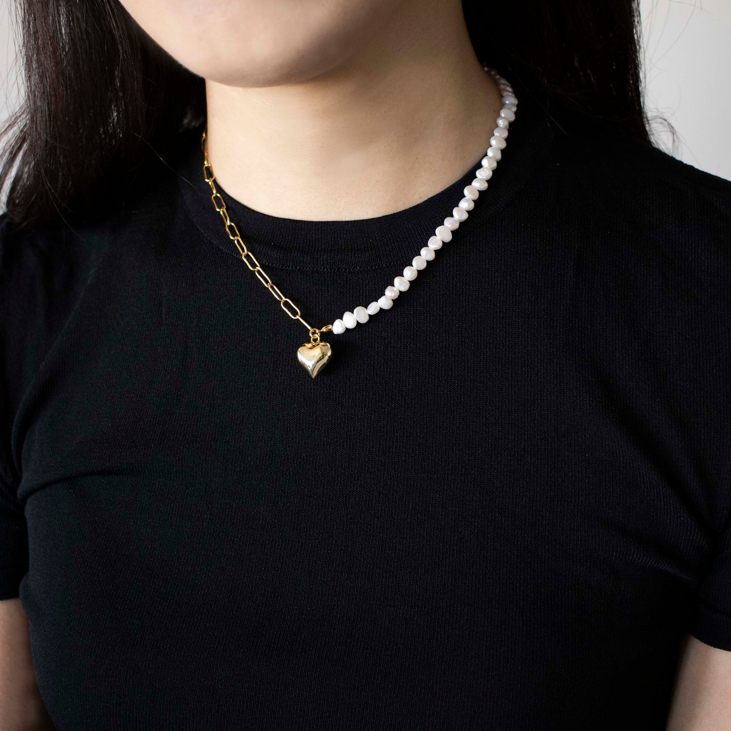 This stylish piece features a half chain with baroque pearls and other half an alta chain with a heart pendant.