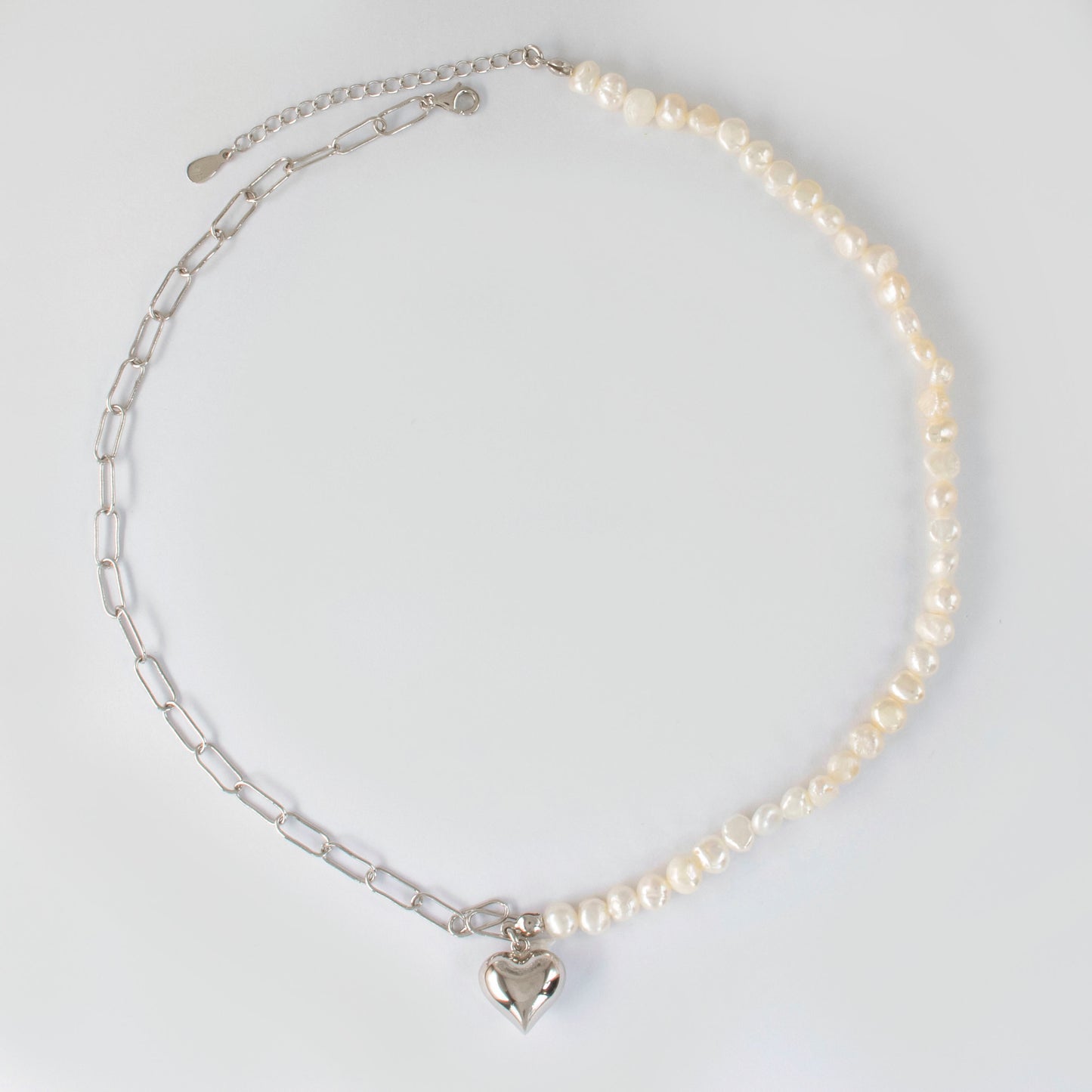 This stylish piece features a half chain with baroque pearls and other half an alta chain with a heart pendant.