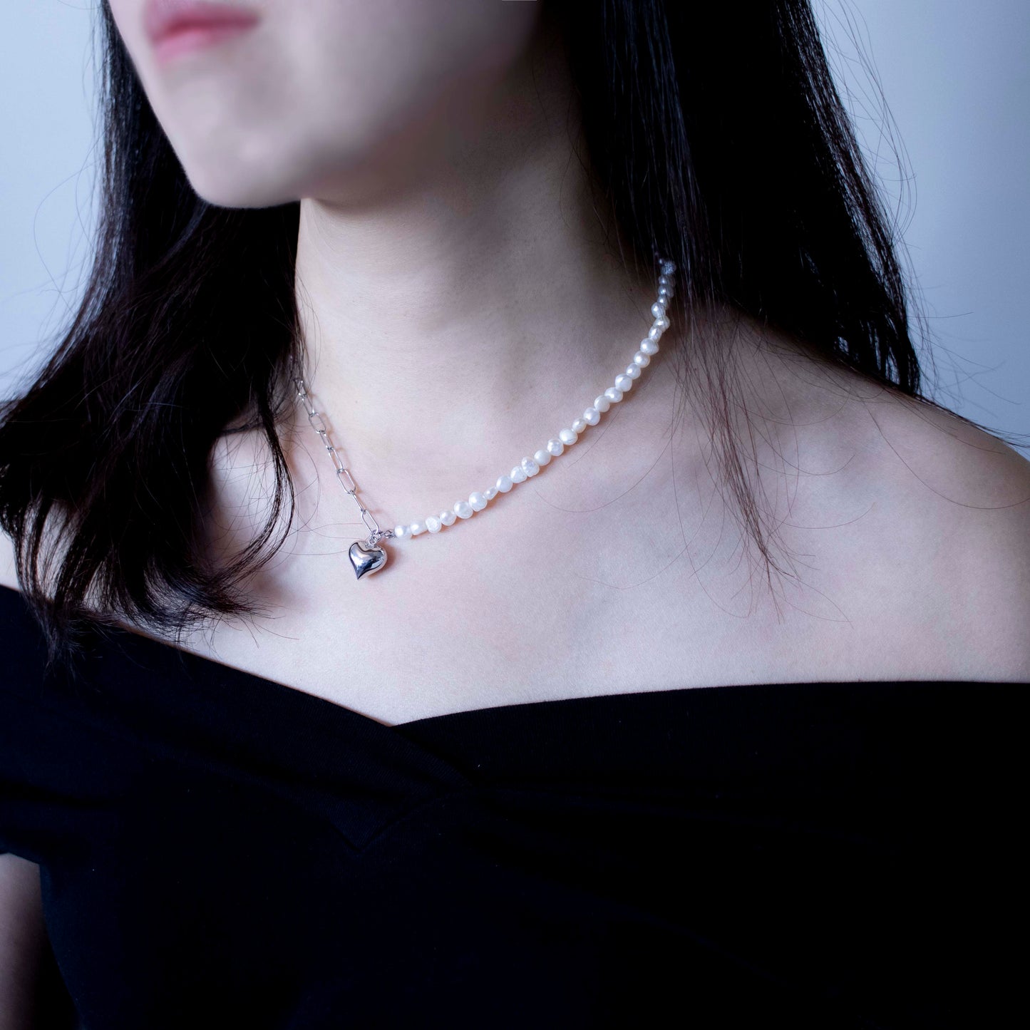 This stylish piece features a half chain with baroque pearls and other half an alta chain with a heart pendant.