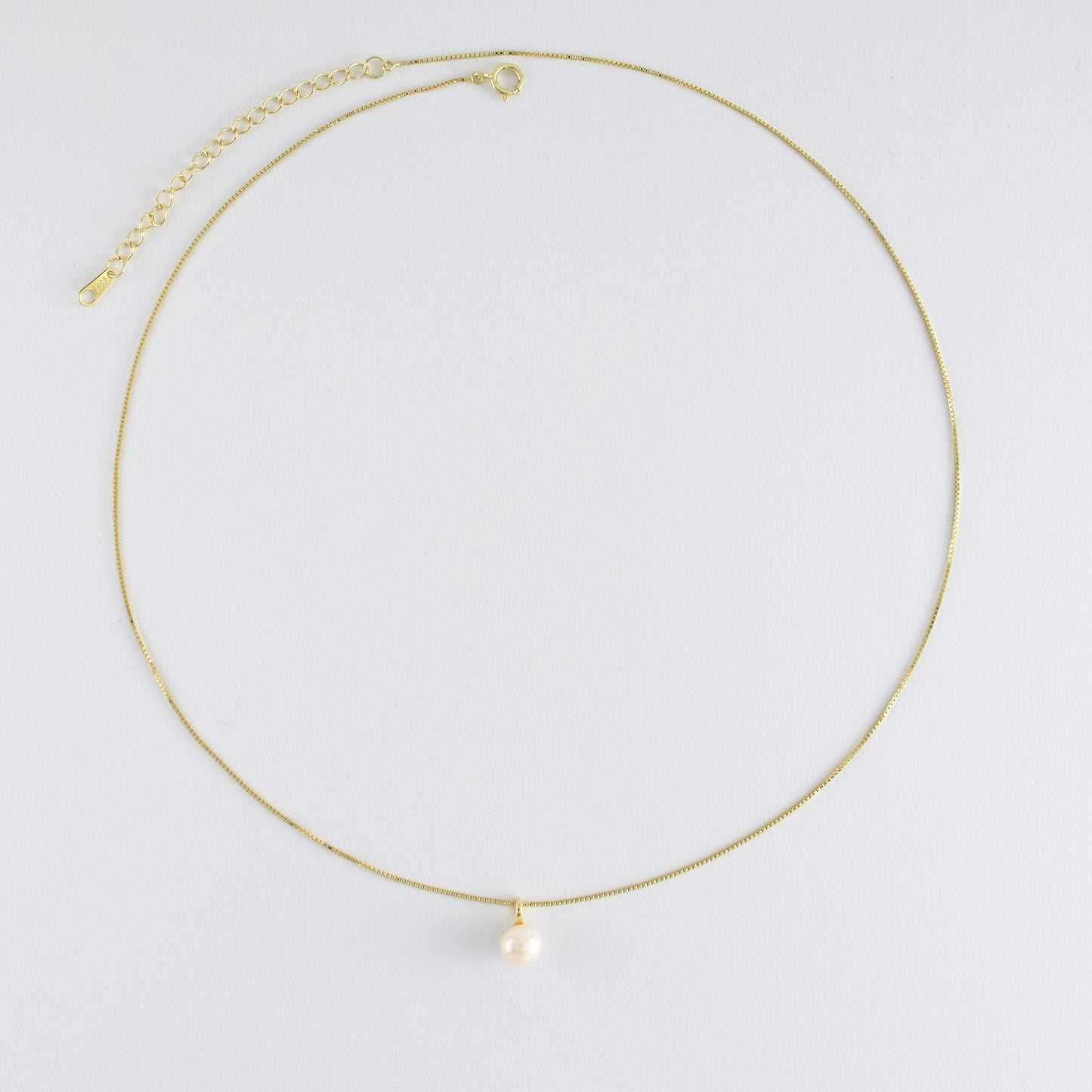 A lustrous round freshwater pearl drapes from the chain.