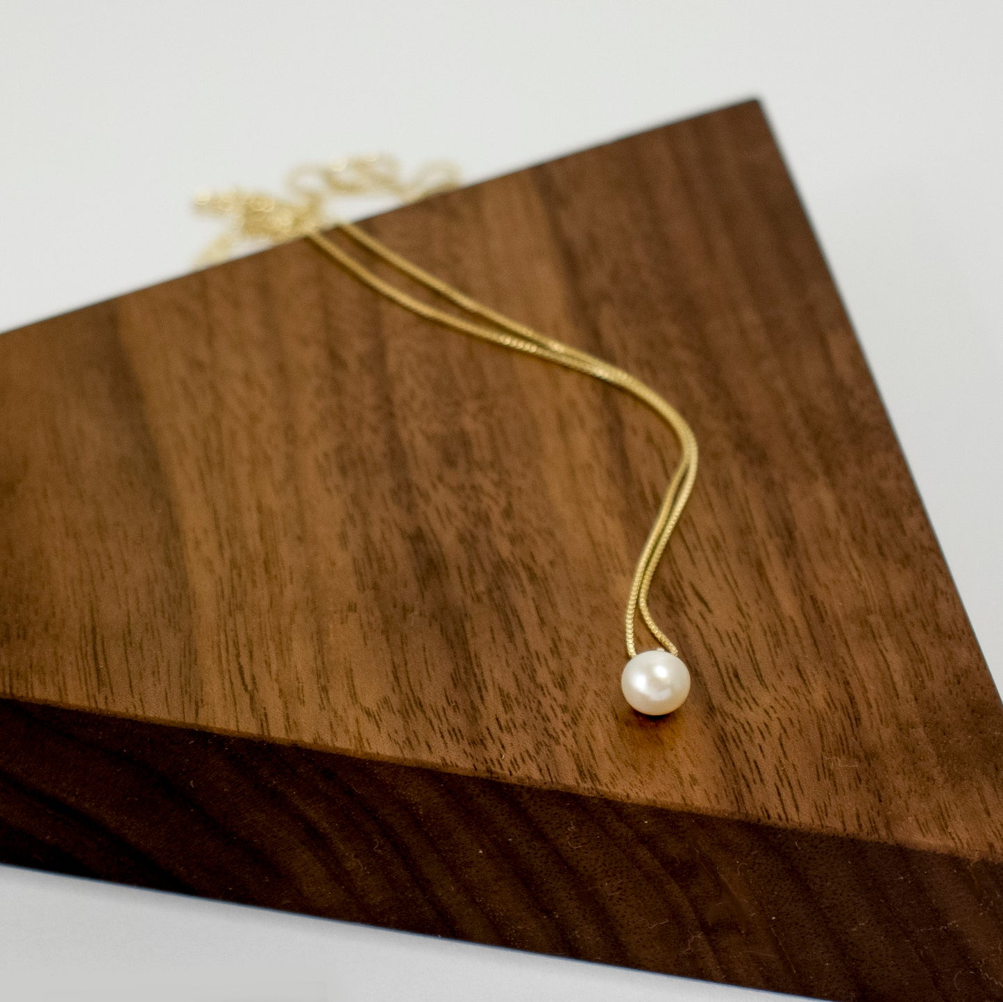 A lustrous round freshwater pearl drapes from the chain.