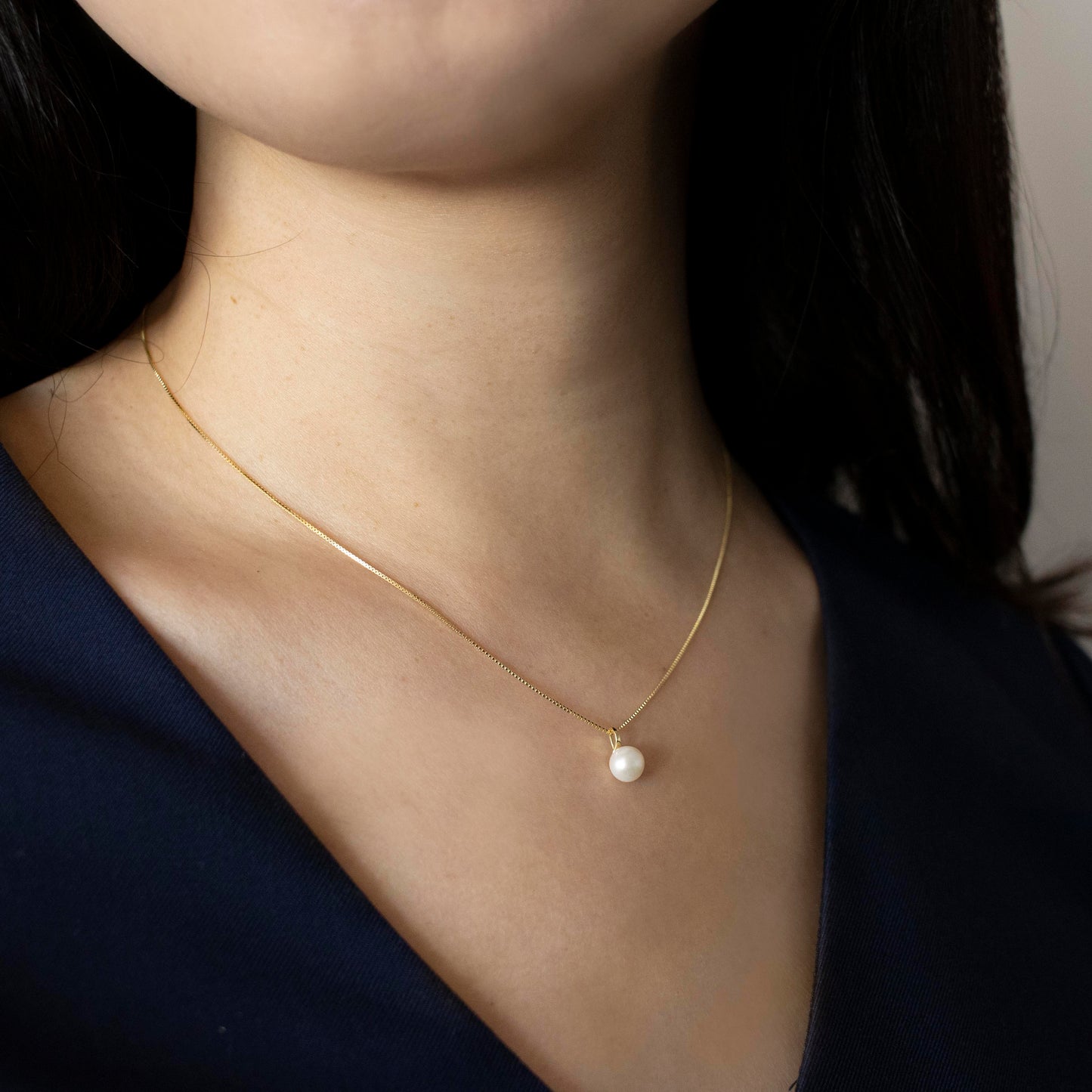A lustrous round freshwater pearl drapes from the chain.