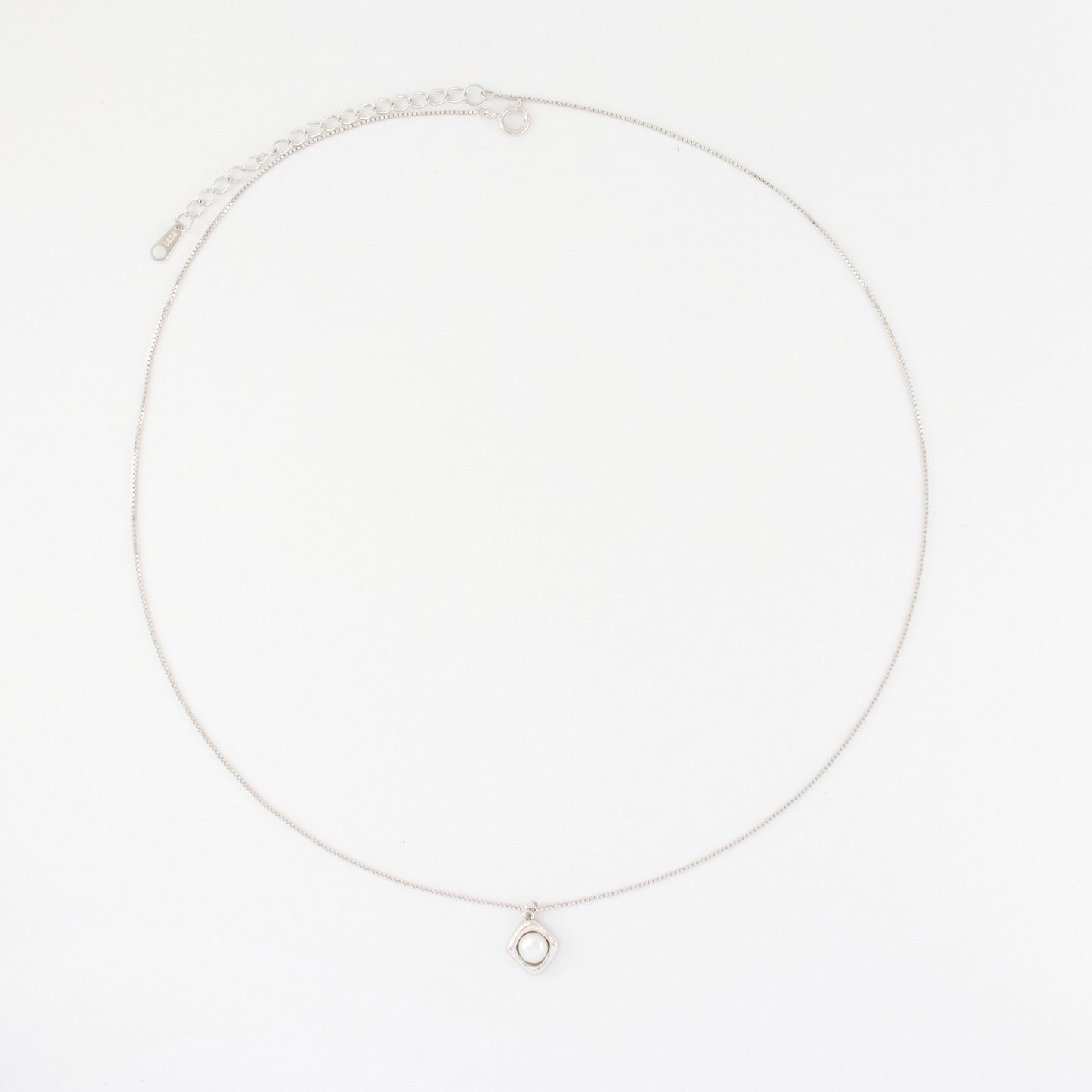 A rhombus pendant embraces a button pearl