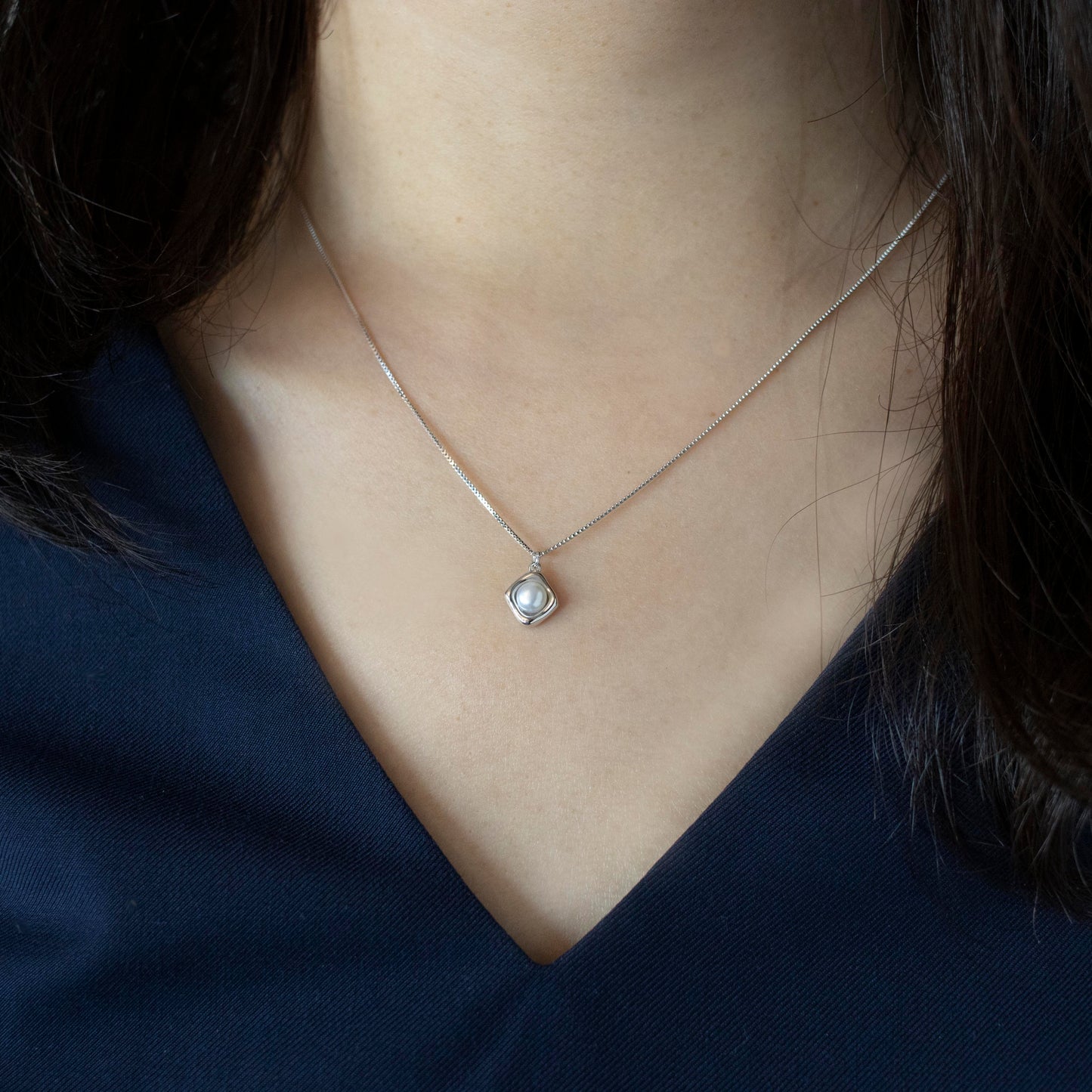 A rhombus pendant embraces a button pearl