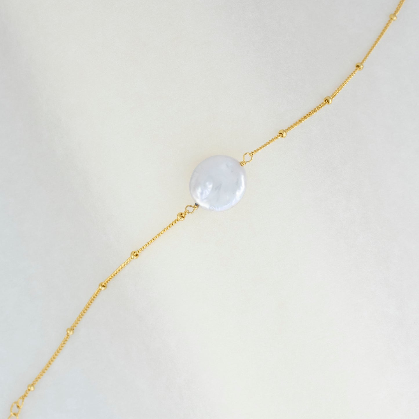 A sizable baroque pearl adorns the delicate beaded chain of this bracelet, radiating simplicity and charm.