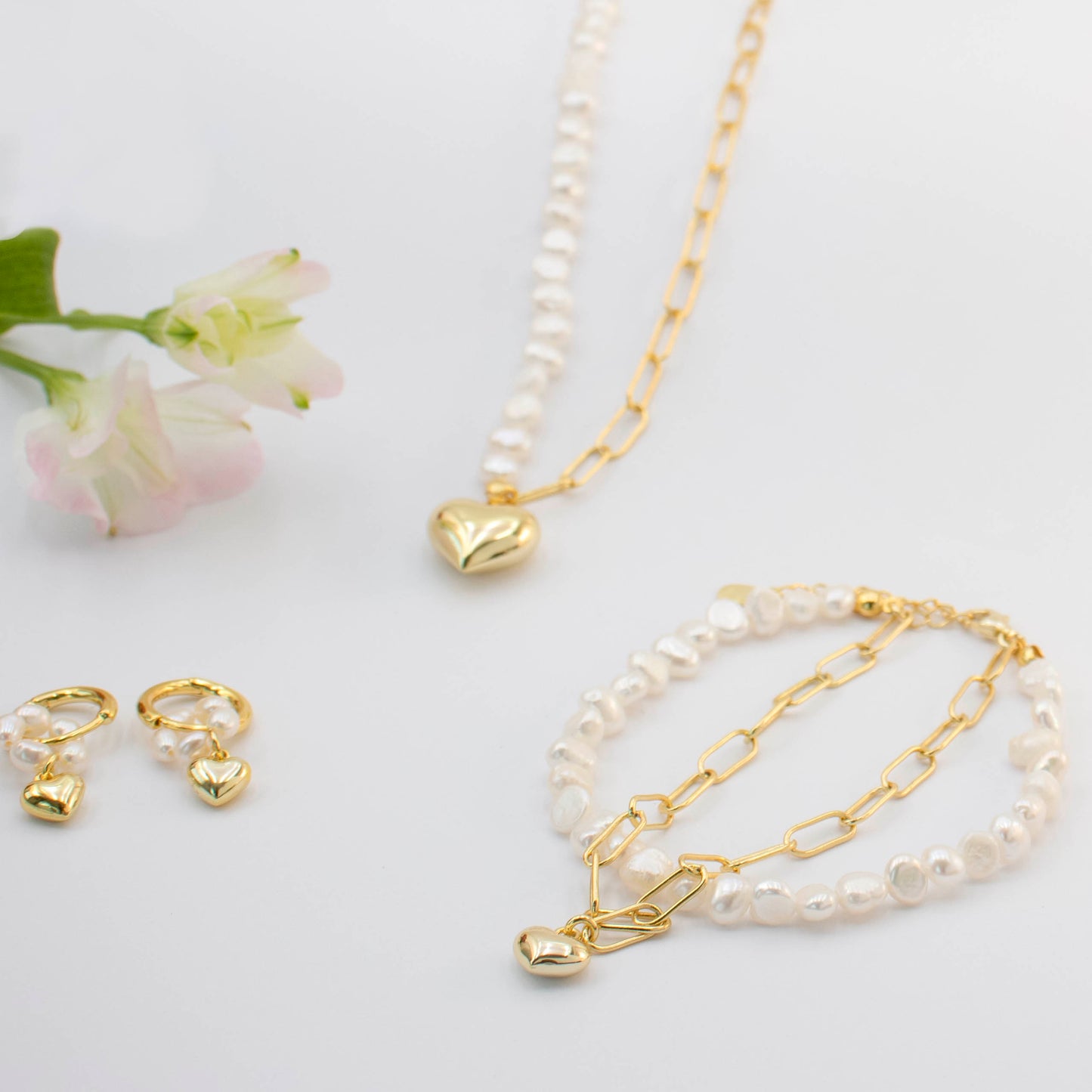 This stylish piece features a dual chain with baroque pearls and an alta chain with a heart pendant.