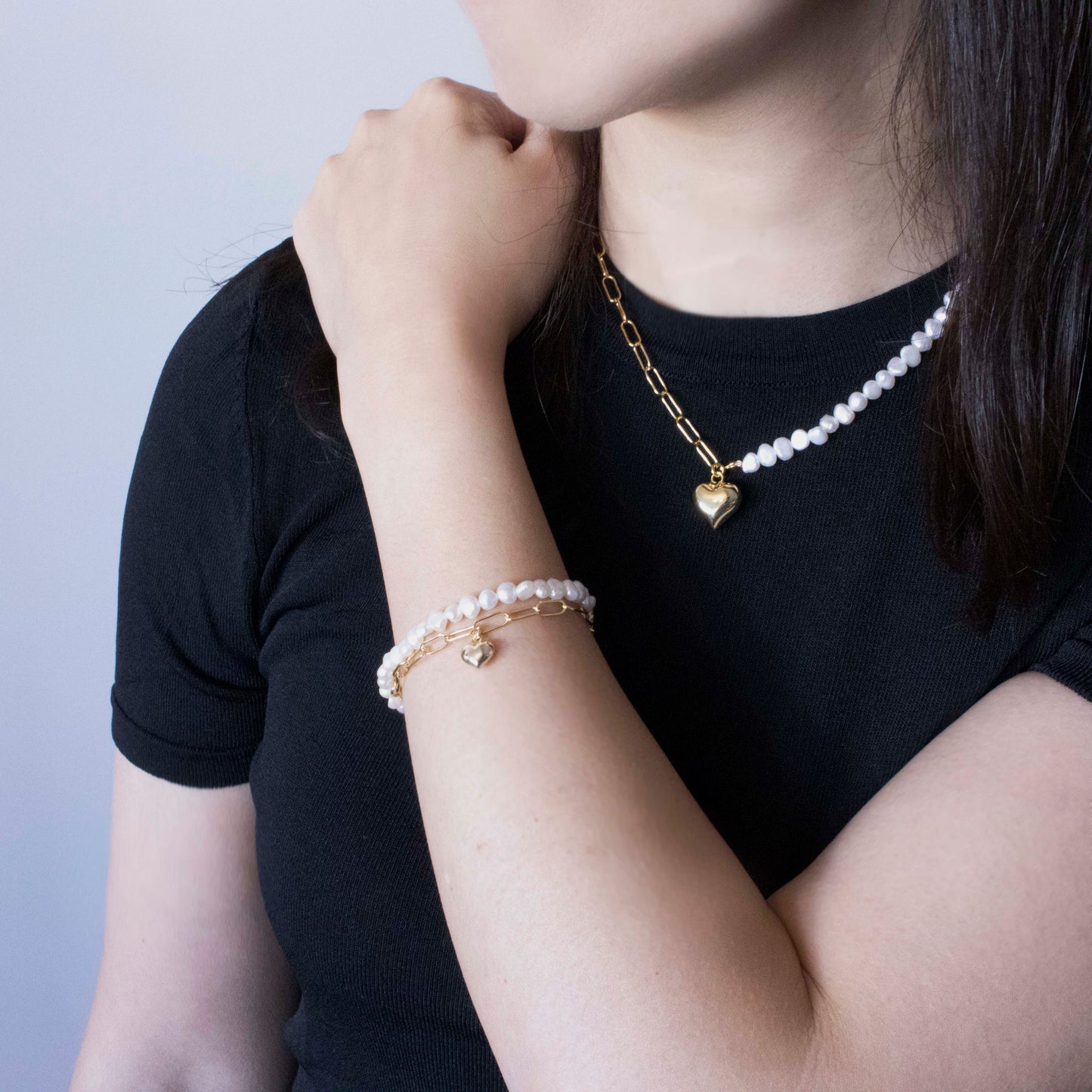 This stylish piece features a dual chain with baroque pearls and an alta chain with a heart pendant.