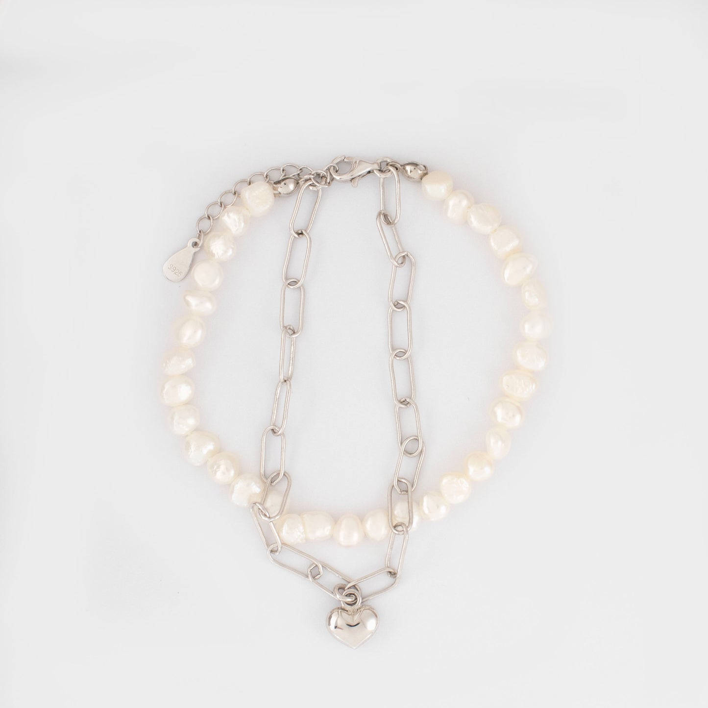 This stylish piece features a dual chain with baroque pearls and an alta chain with a heart pendant.