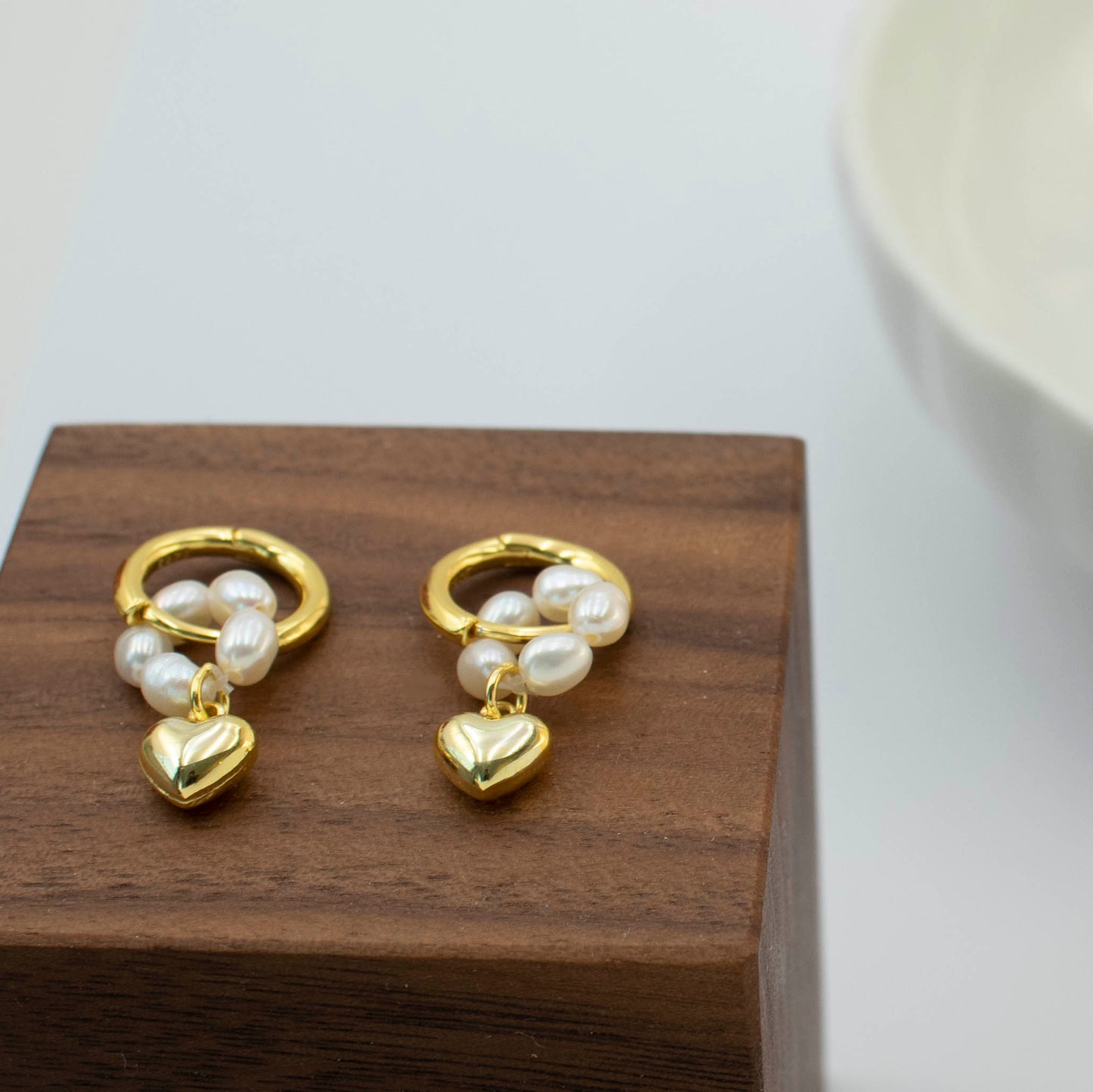 This stylish piece features a pearl-ring with a heart pendant.