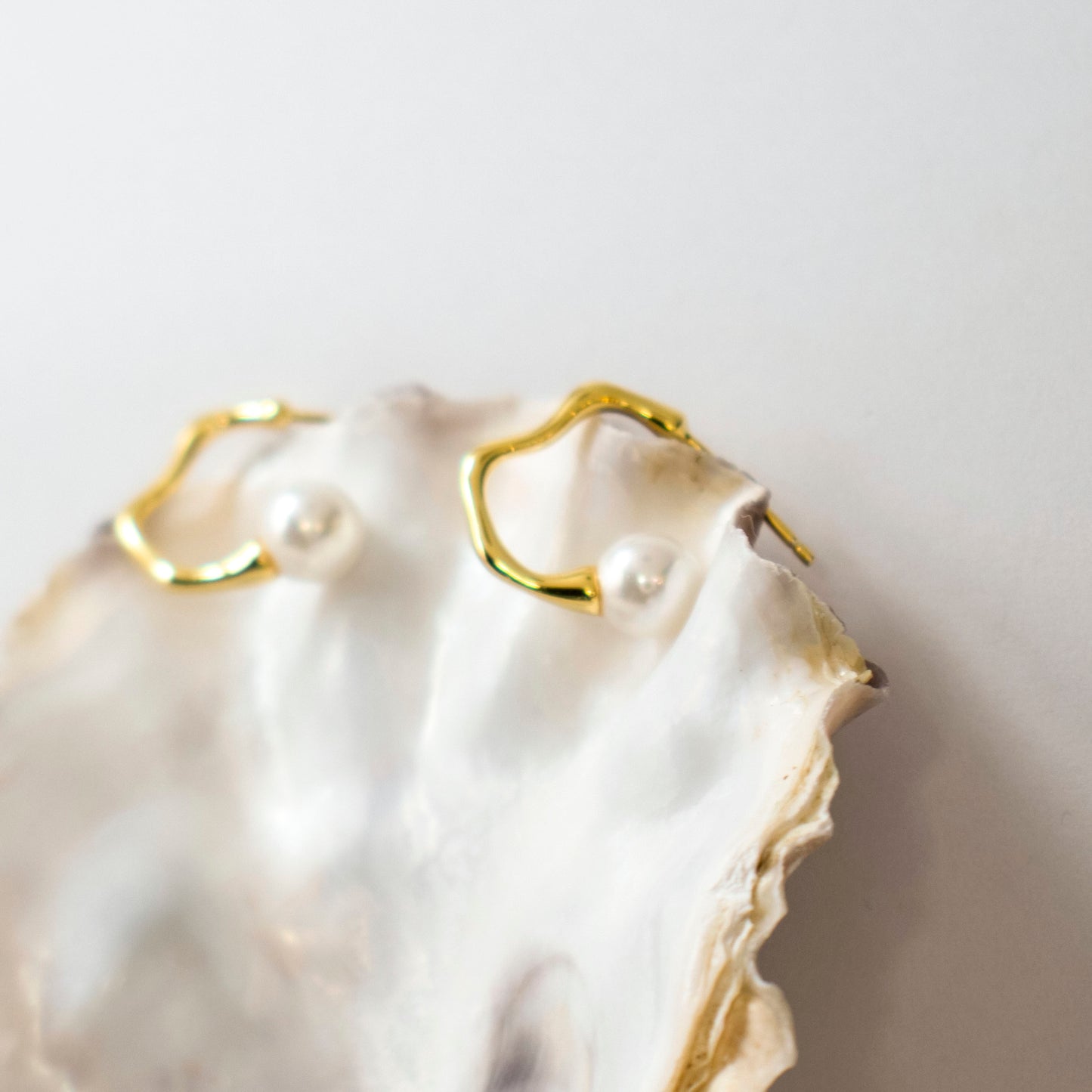 Aquata, lustrous round pearl with an undulating gold stud earrings.