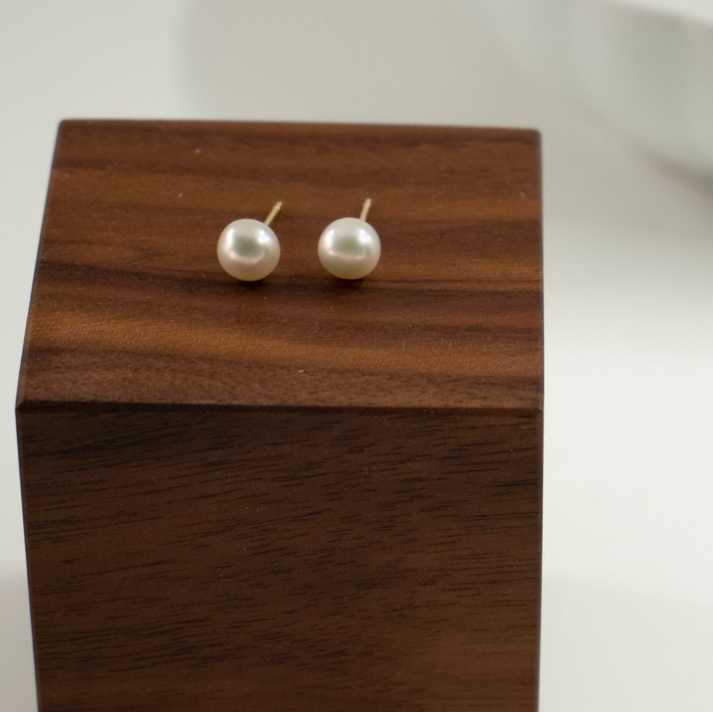 A solitary semi-round pearl adorns the stud.