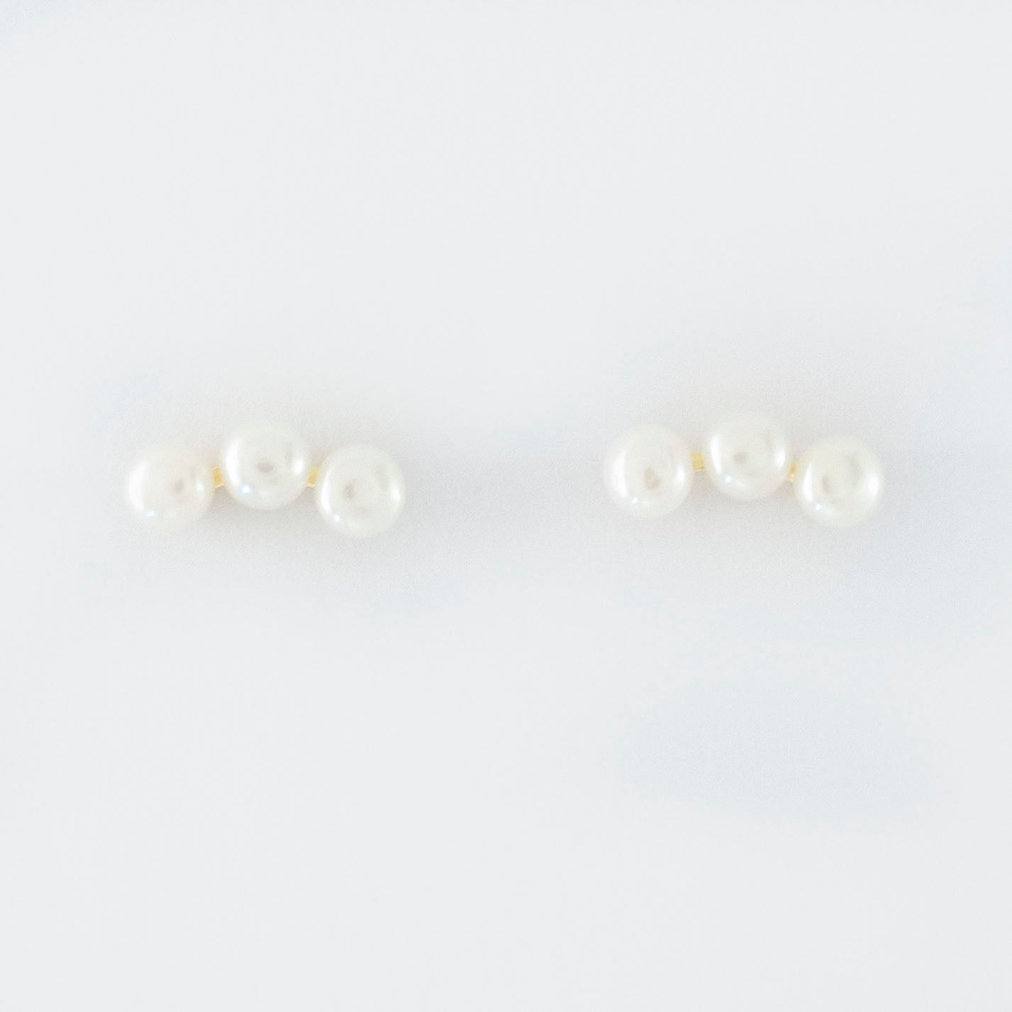 Three freshwater pearls are arranged in an arc on the earrings.