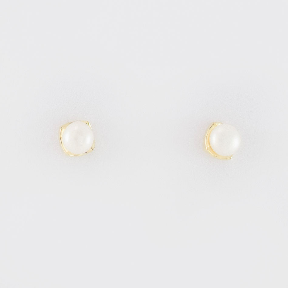 A rhombus stud earring embraces a button pearl.