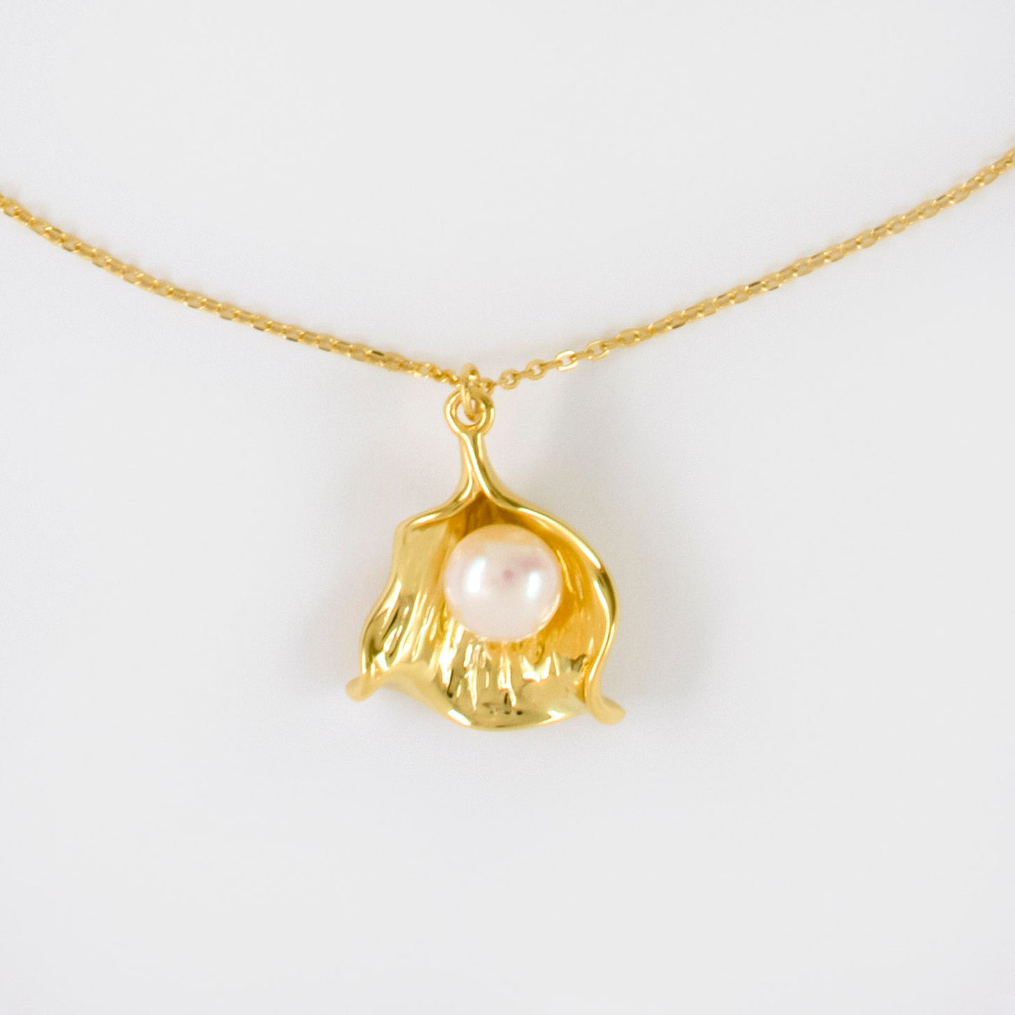 Necklace Venus features a round pearl encased within a shell pendant charm.