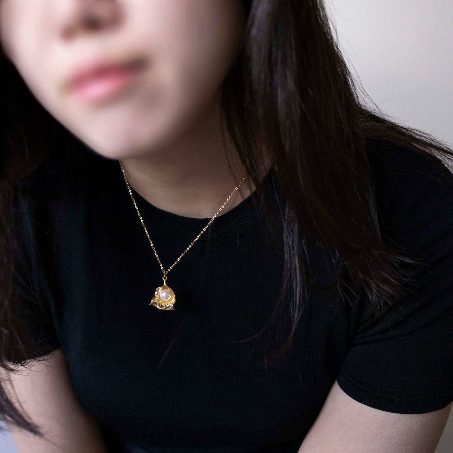 Necklace Venus features a round pearl encased within a shell pendant charm.